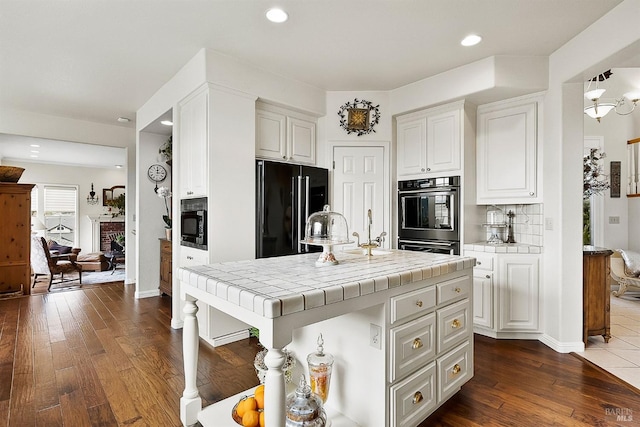 kitchen with decorative backsplash, white cabinets, black appliances, tile countertops, and dark wood-type flooring