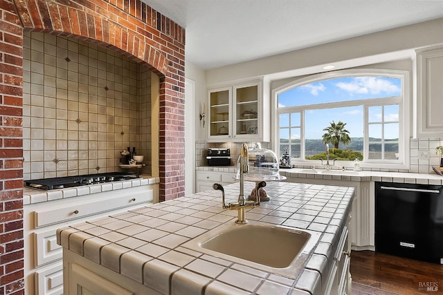 kitchen featuring black dishwasher, gas cooktop, tile countertops, and decorative backsplash