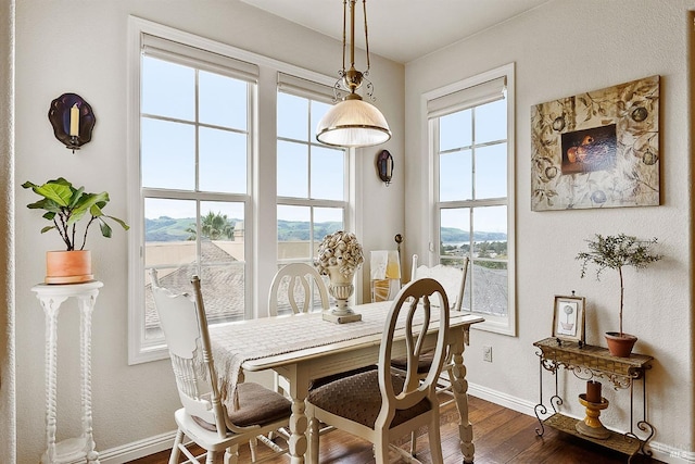dining room featuring dark wood-style flooring, a mountain view, and baseboards