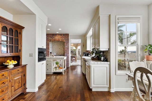 kitchen with black microwave, tile counters, white cabinetry, and dark wood-type flooring