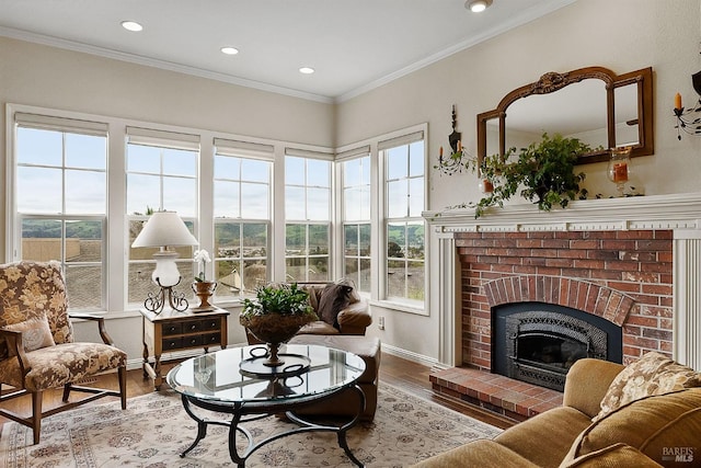 interior space featuring recessed lighting, wood finished floors, a brick fireplace, baseboards, and crown molding