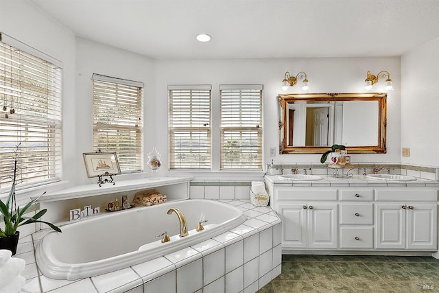 bathroom with a bath, double vanity, and a sink