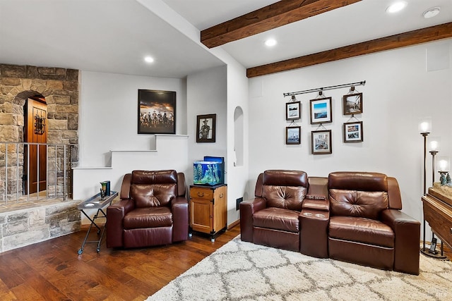 living area with recessed lighting, beam ceiling, a stone fireplace, arched walkways, and wood finished floors