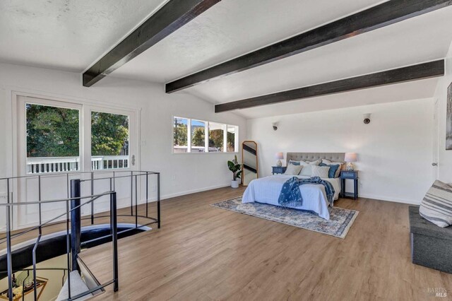 bedroom with baseboards, wood finished floors, and vaulted ceiling with beams