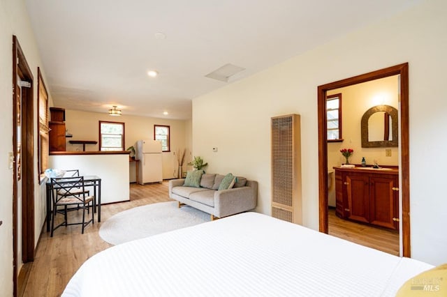 27821 Ten Mile Rd, Point Arena, CA 95468 - bedroom with connected bathroom, a heating unit, light wood-style flooring, freestanding refrigerator, and recessed lighting