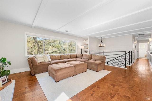 living area with beam ceiling, baseboards, an inviting chandelier, visible vents, and hardwood / wood-style floors