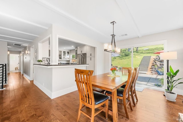 dining room featuring baseboards, visible vents, hardwood / wood-style flooring, and beam ceiling