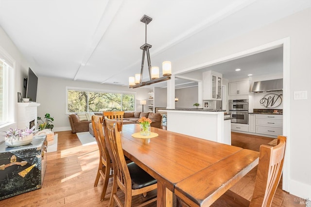 dining room featuring a fireplace, light wood-type flooring, and baseboards
