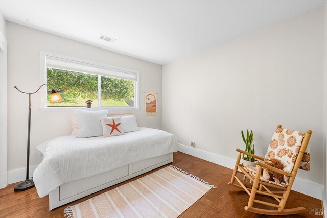 bedroom featuring baseboards, wood finished floors, and visible vents