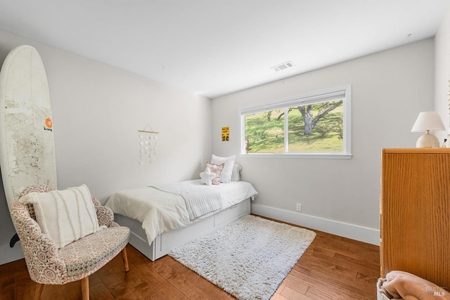 bedroom with wood finished floors, visible vents, and baseboards