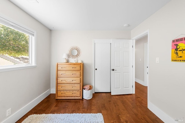 bedroom with baseboards and dark wood-type flooring