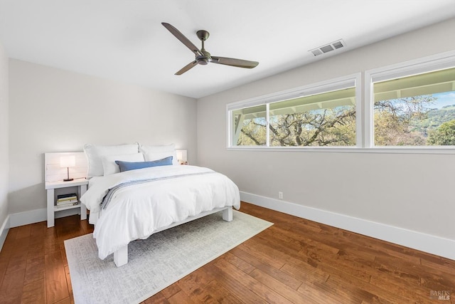 bedroom featuring wood finished floors, visible vents, a ceiling fan, and baseboards
