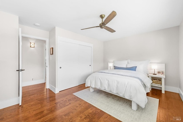 bedroom featuring wood finished floors, a closet, baseboards, and ceiling fan