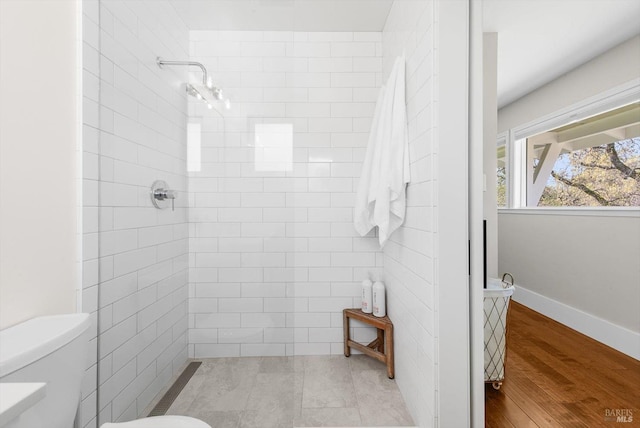 full bathroom with wood finished floors, toilet, and tiled shower