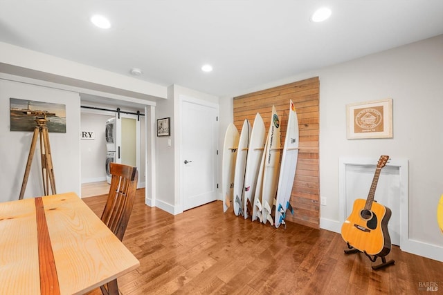 office area with a barn door, wood finished floors, baseboards, and stacked washer / dryer