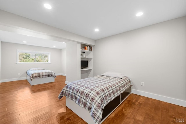 bedroom with baseboards, wood finished floors, and recessed lighting