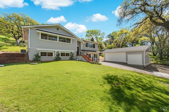 raised ranch featuring an outbuilding, central air condition unit, a front yard, and a detached garage