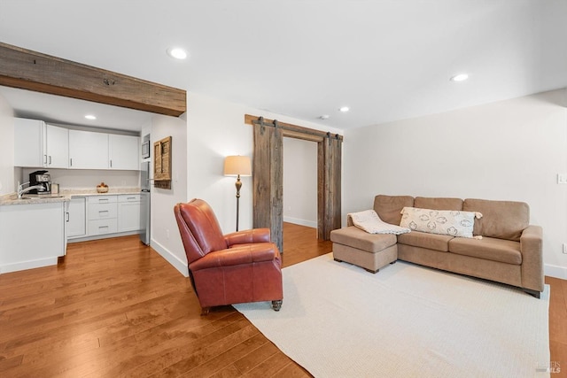 living area featuring a barn door, light wood-style flooring, baseboards, and recessed lighting