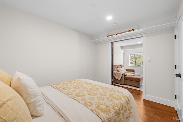 bedroom with baseboards, wood finished floors, and recessed lighting