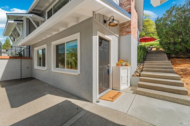 doorway to property featuring stucco siding, a chimney, and a patio area