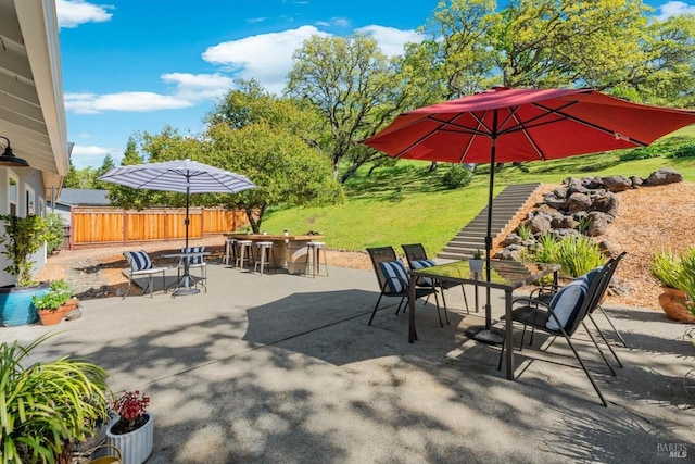view of patio / terrace with outdoor dry bar, outdoor dining space, and fence