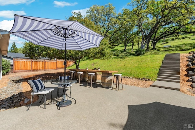 view of patio featuring outdoor dry bar and fence