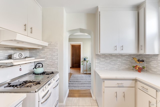 36 Wilson Ave, Vallejo, CA 94590 - kitchen with white range with gas stovetop, light stone countertops, under cabinet range hood, arched walkways, and tasteful backsplash