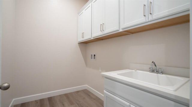 laundry room featuring baseboards, light wood-style flooring, cabinet space, a sink, and washer hookup