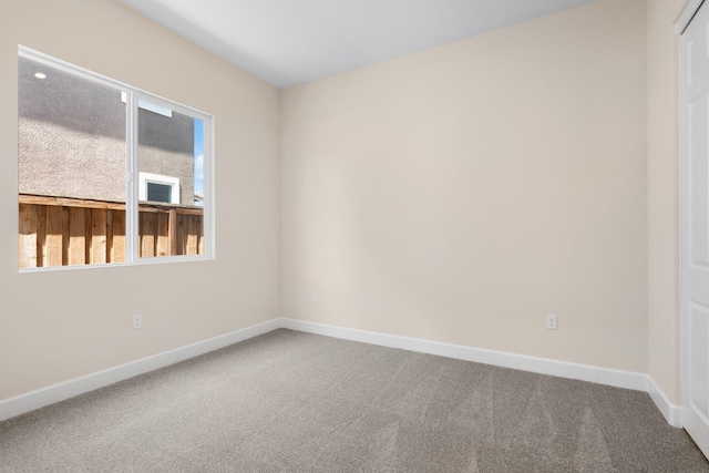 spare room featuring carpet floors and baseboards