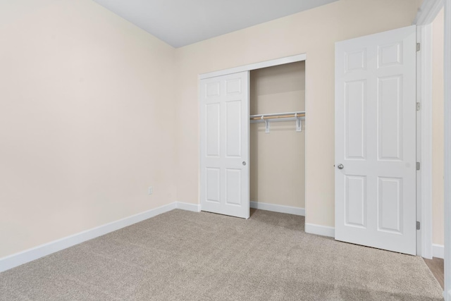 unfurnished bedroom featuring carpet floors, baseboards, and a closet