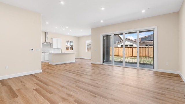 unfurnished living room with recessed lighting, a sink, light wood finished floors, and a healthy amount of sunlight