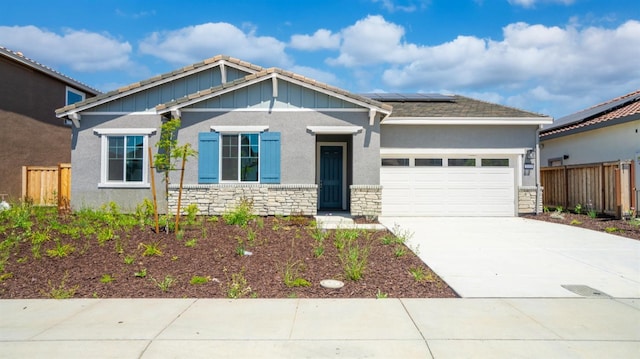 craftsman inspired home with an attached garage, fence, solar panels, and stone siding