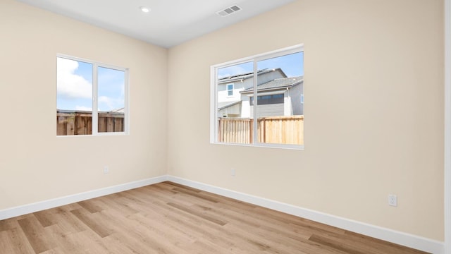 empty room with baseboards, recessed lighting, wood finished floors, and visible vents