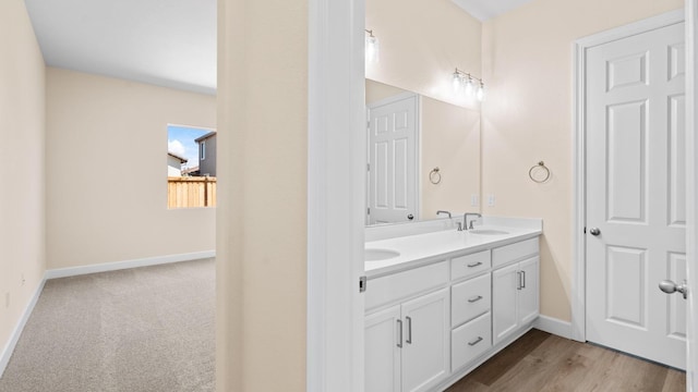 bathroom with double vanity, a sink, and baseboards