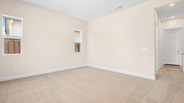 unfurnished room with baseboards, visible vents, and light colored carpet