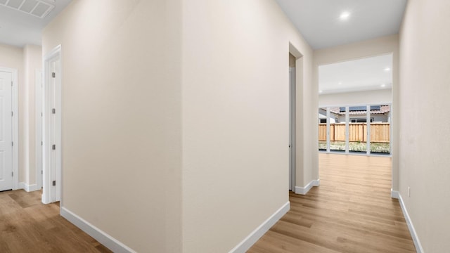 corridor featuring visible vents, light wood finished floors, and baseboards