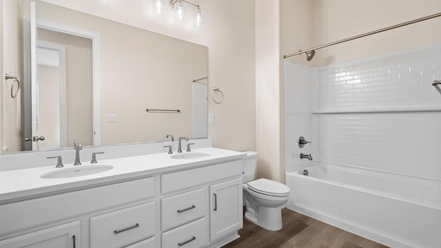full bath featuring a sink, bathtub / shower combination, toilet, and wood finished floors