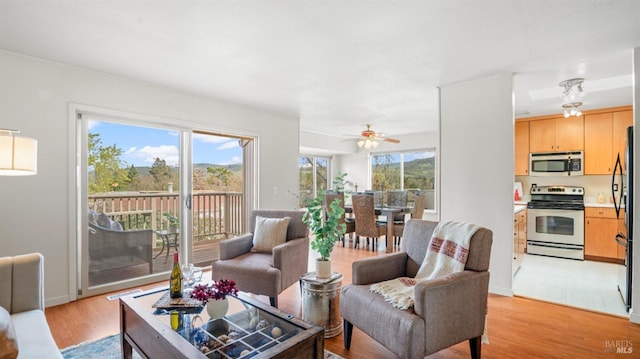 living room featuring plenty of natural light, a ceiling fan, and light wood-style floors