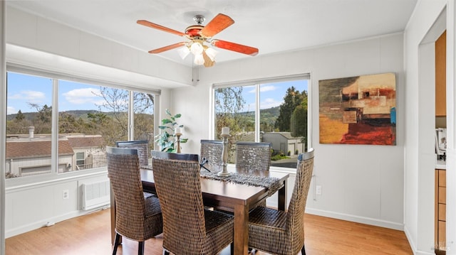 dining room with baseboards, light wood finished floors, and ceiling fan