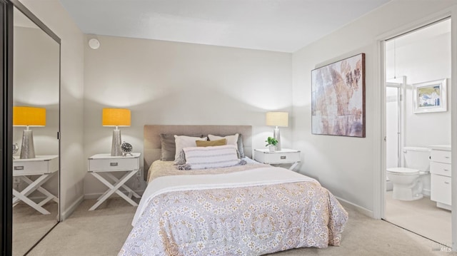 carpeted bedroom featuring connected bathroom and baseboards