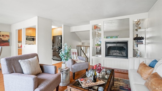 living room with a glass covered fireplace, stairway, and wood finished floors