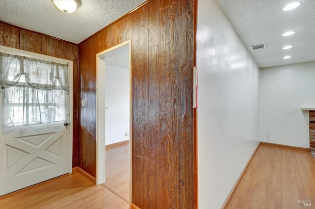 1014 Falcon Dr, Vallejo, CA 94589 - hall with light wood-style flooring, visible vents, wood walls, and a textured ceiling