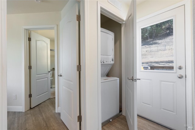 laundry area with light wood finished floors, laundry area, stacked washer and clothes dryer, and visible vents