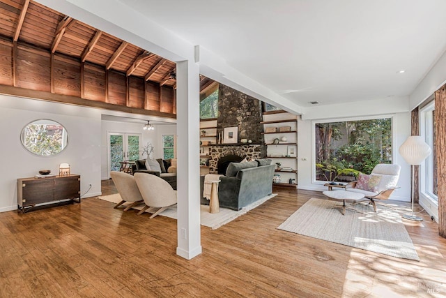 living area with baseboards, wood ceiling, built in features, wood finished floors, and a fireplace