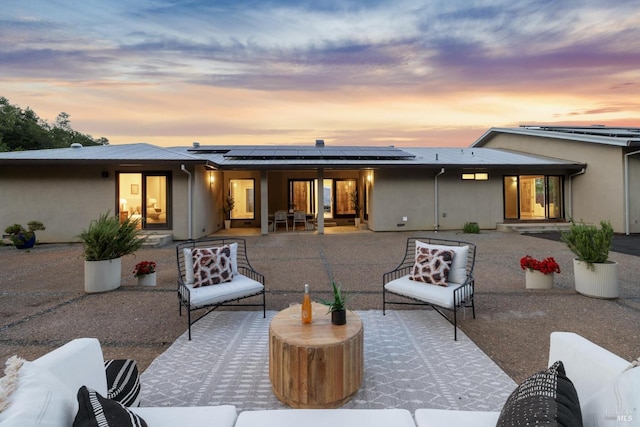 back of house featuring stucco siding, outdoor lounge area, a patio area, and solar panels
