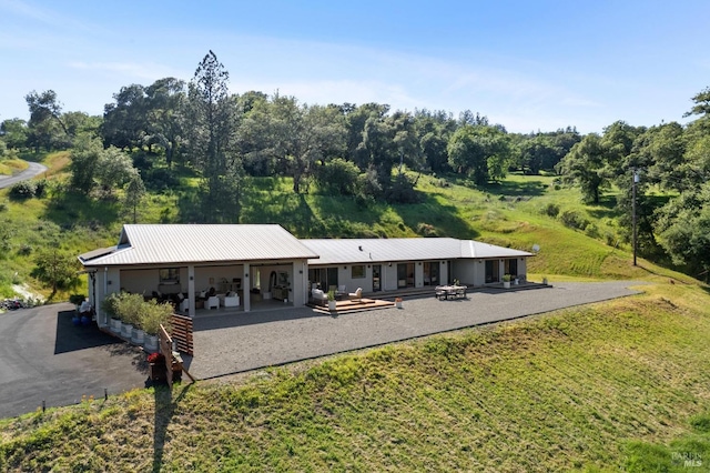 rear view of house with a lawn, a patio area, and metal roof
