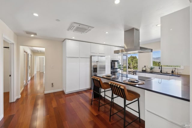 kitchen with dark wood-style flooring, island range hood, modern cabinets, stainless steel appliances, and white cabinetry