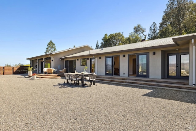 back of house featuring fence, french doors, and stucco siding