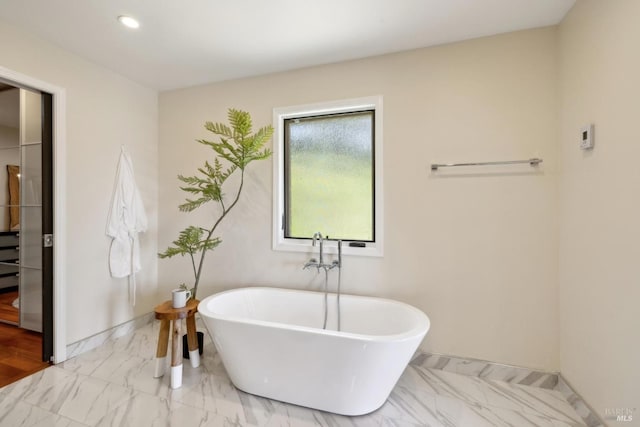full bath featuring recessed lighting, baseboards, a freestanding bath, and marble finish floor