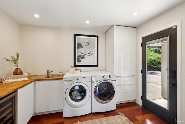 clothes washing area featuring laundry area, a sink, beverage cooler, separate washer and dryer, and dark wood-type flooring